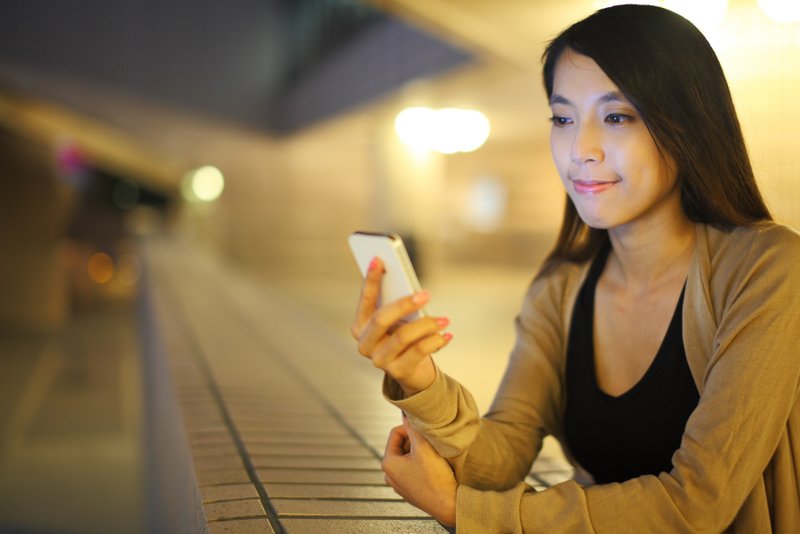 woman using smartphone in city at night